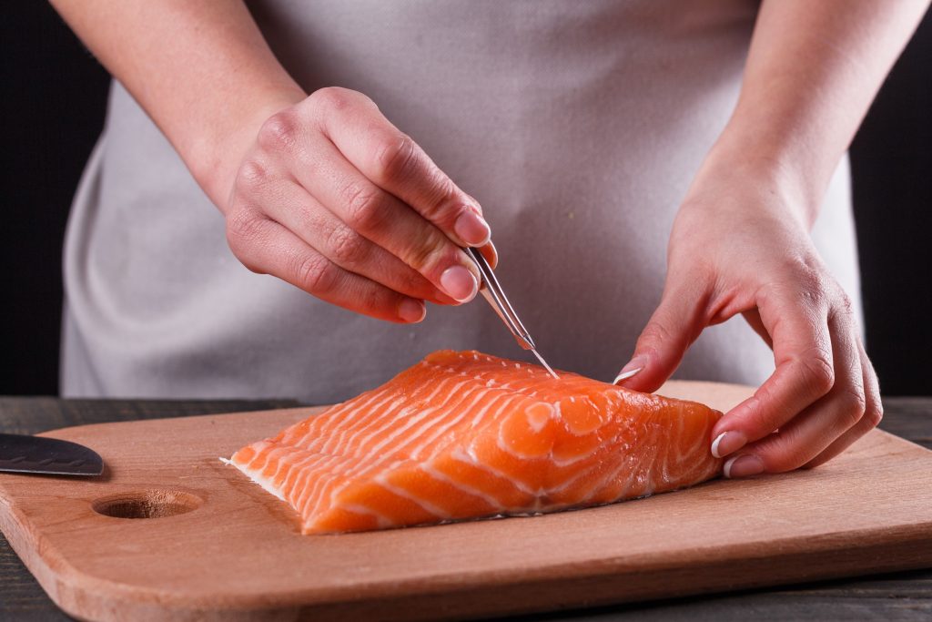 person removing bones from salmon