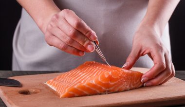 person removing bones from salmon